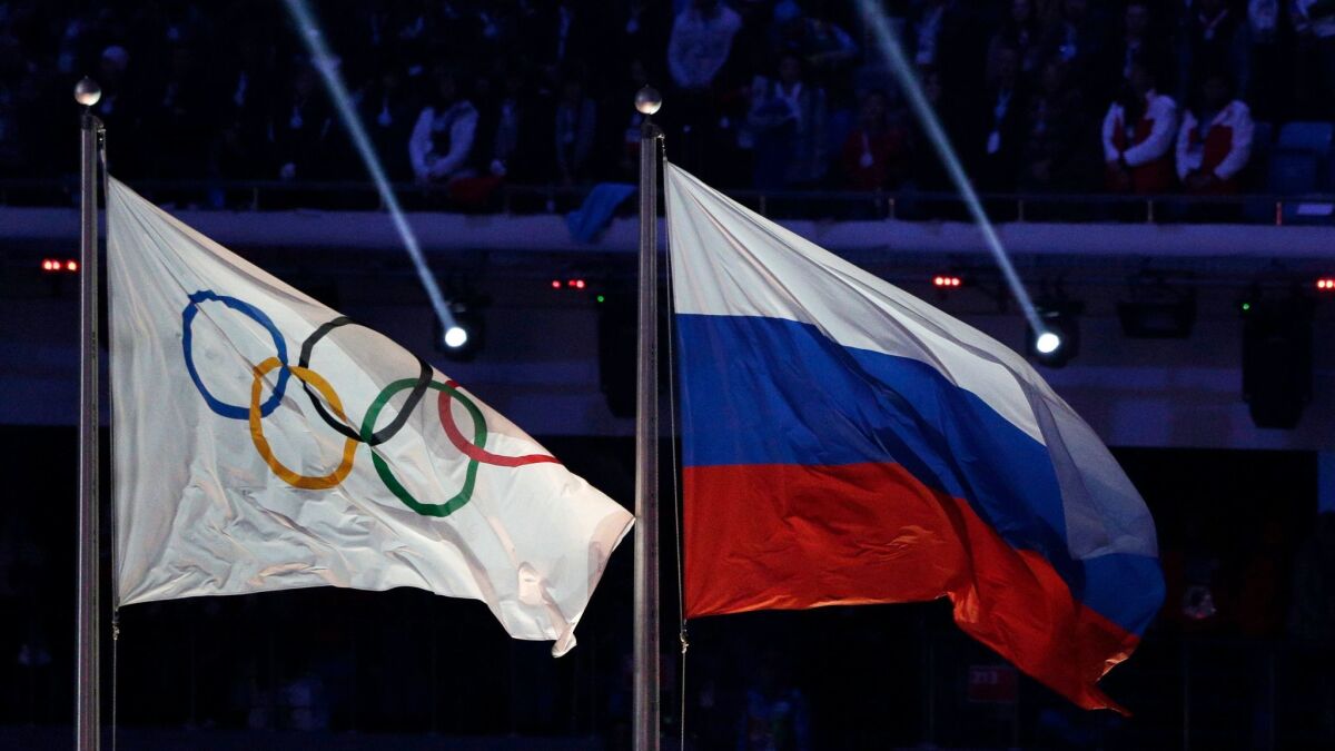 The Russian and Olympic flags fly during the closing ceremony of the Winter Olympics in Sochi, Russia, on Feb. 23, 2014.