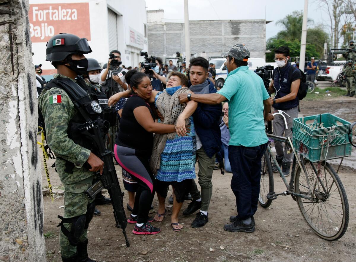 A woman receives assistance near the rehabilitation facility where 26 people were killed in Irapuato, Mexico. 
