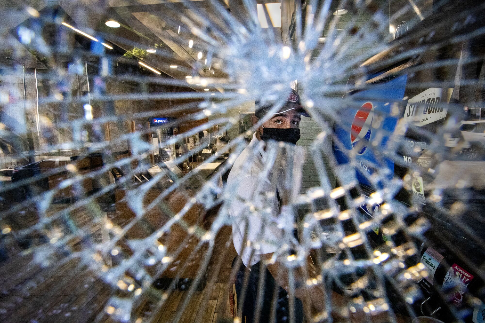 A Jersey Mike's employee is seen making a sandwich through one of several shattered windows on Monday in Los Angeles.