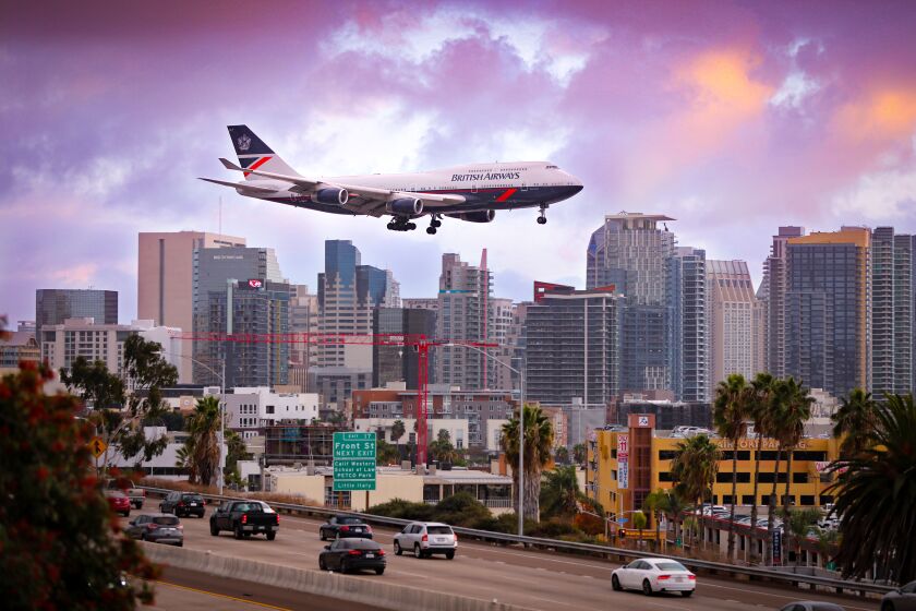 A British Airways Boeing 747 wearing a Landor retro paint scheme used by the airline between 1984 and 1987, passes over Interstate 5 with a backdrop of the downtown San Diego skyline moments away from arriving at San Diego International Airport from London, December 14. The plane is one of several that have been painted with past designs as part of the 100th anniversary of the airline which turned 100 August 25.