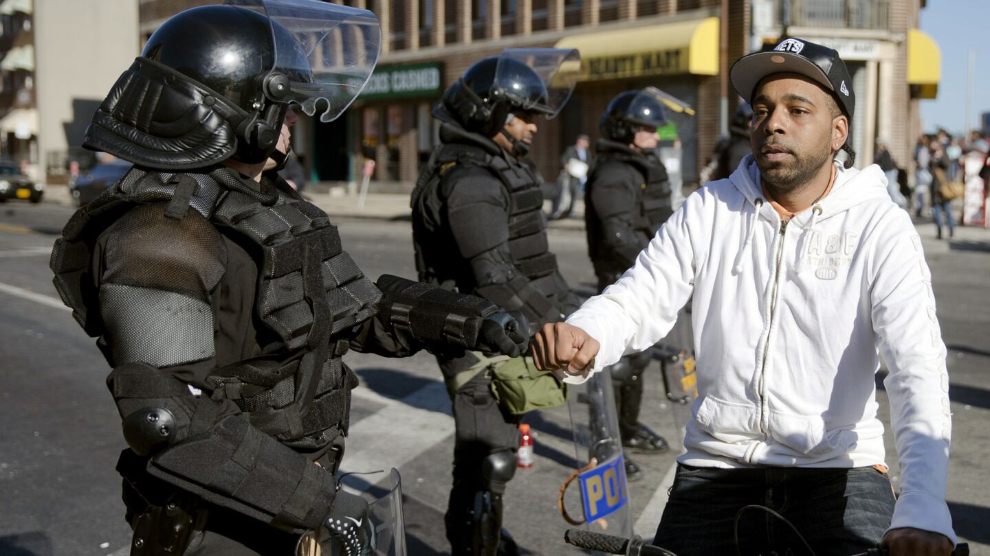 A man on a bicycle greets Maryland state troopers April 28 in the aftermath of rioting in Baltimore following the funeral for Freddie Gray.