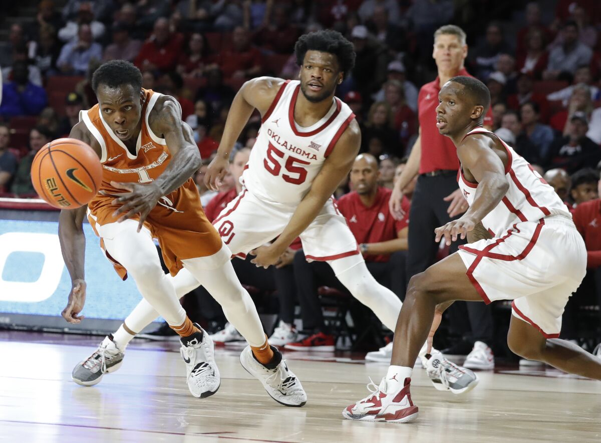 Texas guard Andrew Jones (1) races after a loose ball as Oklahoma guard Elijah Harkless (55) watches during the first half of an NCAA college basketball game Tuesday, Feb. 15, 2022, in Norman, Okla. (AP Photo/Alonzo Adams)