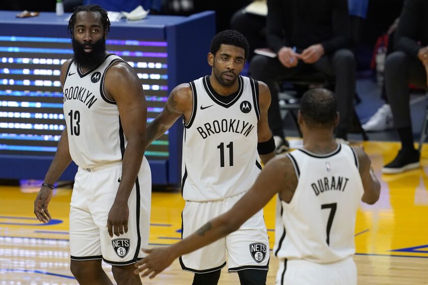 Brooklyn Nets guard Kyrie Irving, middle, gathers with guard James Harden (13) and forward Kevin Durant (7) during the second half of the team's NBA basketball game against the Golden State Warriors in San Francisco, Saturday, Feb. 13, 2021. (AP Photo/Jeff Chiu)