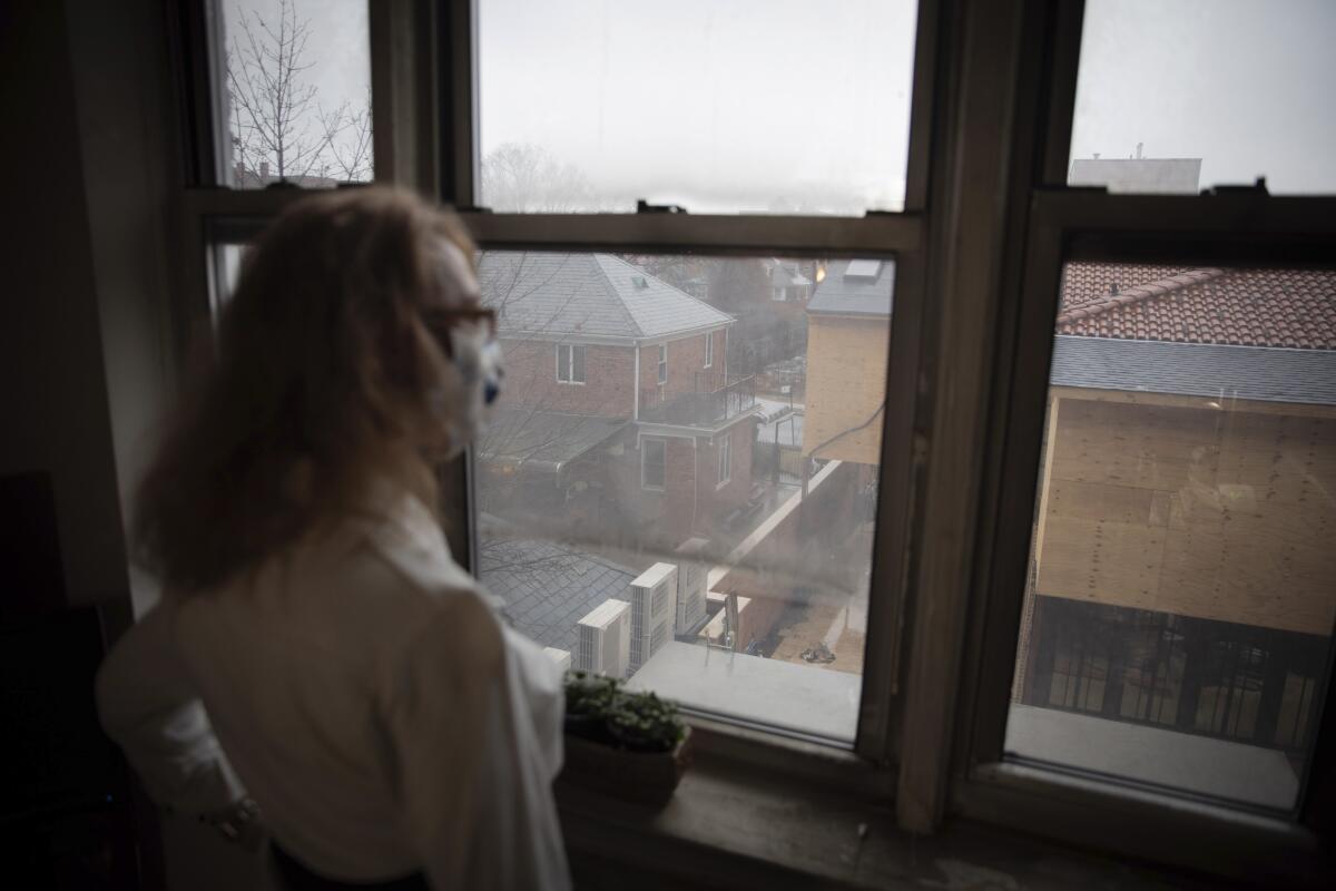 Bonney Ginett looks out the window of her apartment in the Queens borough of New York. 