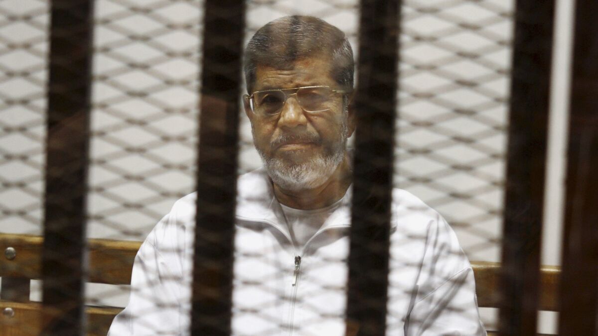 Egypt's ousted Islamist president, Mohamed Morsi, sits in a defendant cage at the police academy courthouse in Cairo in May 2014.