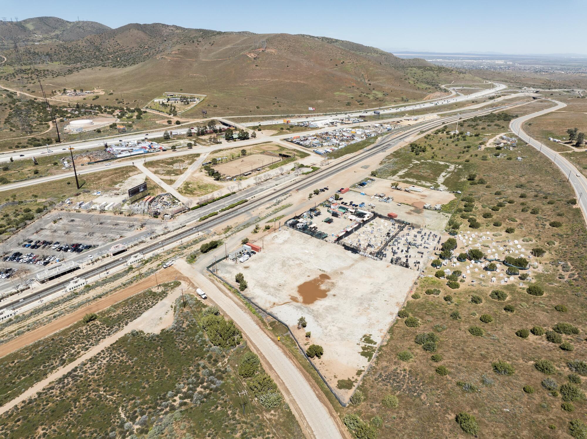 A bird's-eye view of a hilly desert landscape with transportation routes running through it