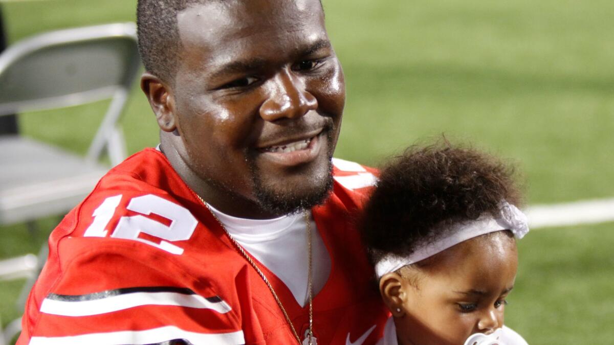 Cardale Jones speaks to reporters while holding his daughter Chloe during Ohio State's football media day Aug. 16, 2015.