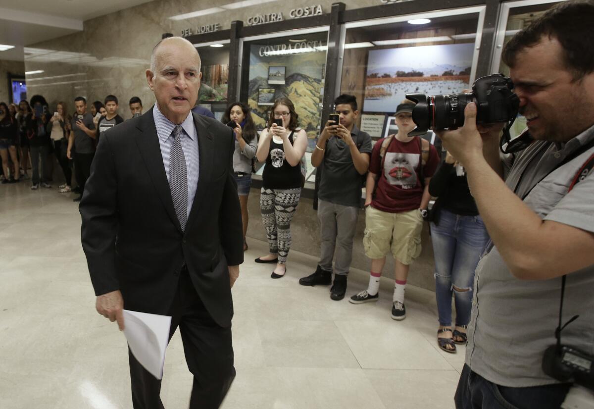 California Gov. Jerry Brown returns to his office Friday after a news conference in which he released his revised 2016-17 state budget plan.
