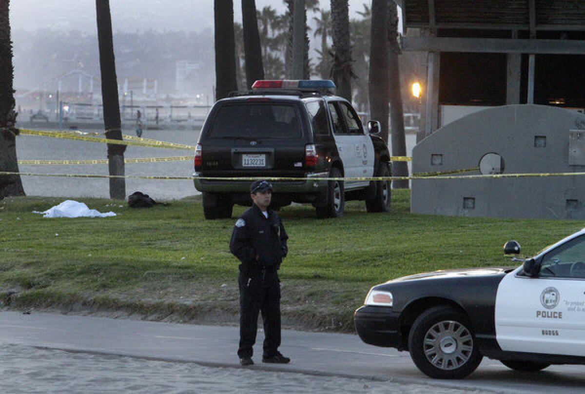 An LAPD officer stands near a body found Wednesday evening by the Venice boardwalk near Breeze Avenue.