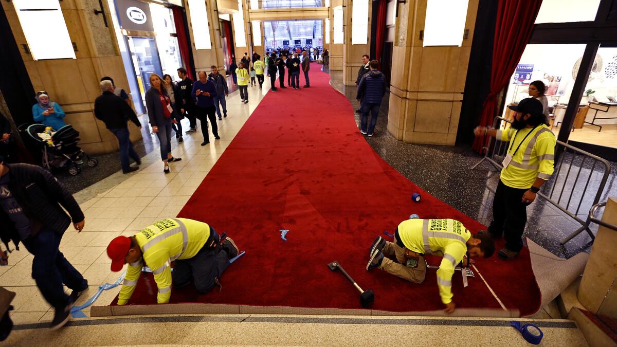 Alvarado Contreras, from left, Rene Palma and Edgar Ochoa cut into place a roll of red carpet in the Dolby Theatre's forecourt. (Al Seib / Los Angeles Times)