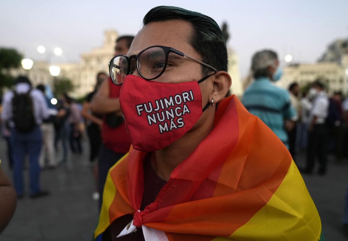 A young man wears a mask against the spread of the new coronavirus that has text that reads in Spanish "Fujimori never more," as demonstrators protest against the decision of Peru's Constitutional Court approving the release from prison of former President Alberto Fujimori in Lima, Peru, Thursday, March 17, 2022. A court official said the court restored a humanitarian pardon granted to Fujimori on Christmas Eve in 2017 by then President Pablo Kuczynski. (AP Photo/Martin Mejia)