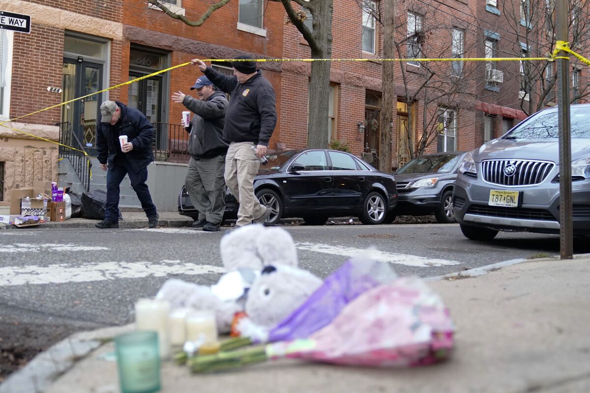 Officials pass flowers and other items left in memory of victims of Wednesday's fatal fire in the Fairmount neighborhood of Philadelphia on Thursday, Jan. 6, 2022. Officials say it's the city's deadliest single fire in at least a century. (AP Photo/Matt Rourke)
