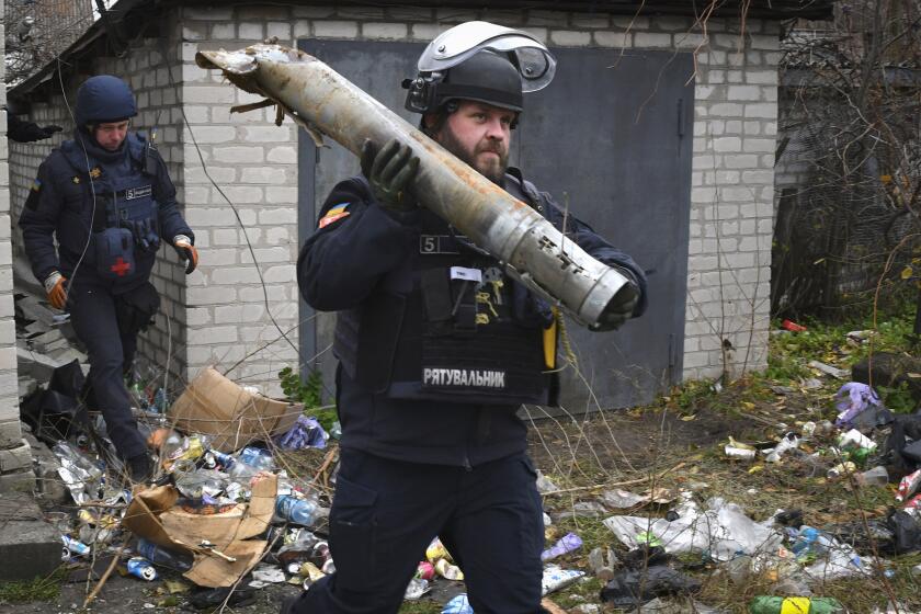 A Ukrainian sapper carries a part of a projectile during a demining operation in a residential area in Lyman, Donetsk region, Ukraine, Wednesday, Nov. 16, 2022. (AP Photo/Andriy Andriyenko)