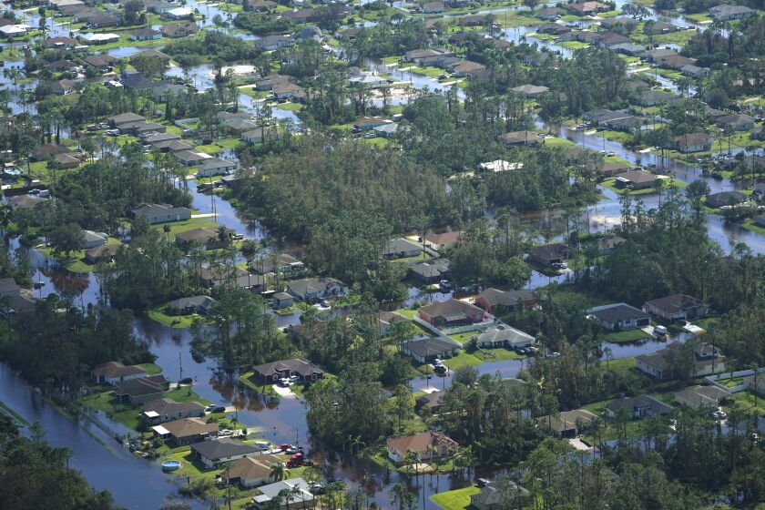 Homes are surrounded by flood waters caused by Hurricane Ian, Thursday, Sept. 29, 2022, in Fort Myers, Fla. Climate change added at least 10% more rain to Hurricane Ian, a study prepared immediately after the storm shows. (AP Photo/Marta Lavandier)