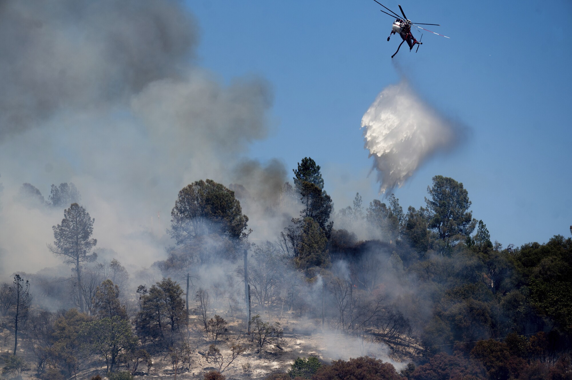 A helicopter drops water on the wildfire.