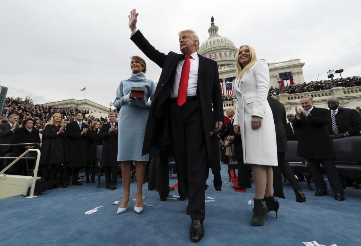 President Trump waves after taking the oath of office as his wife Melania, left, holds a Bible, and daughter Tiffany Trump looks out to the crowd on Friday in Washington, D.C.