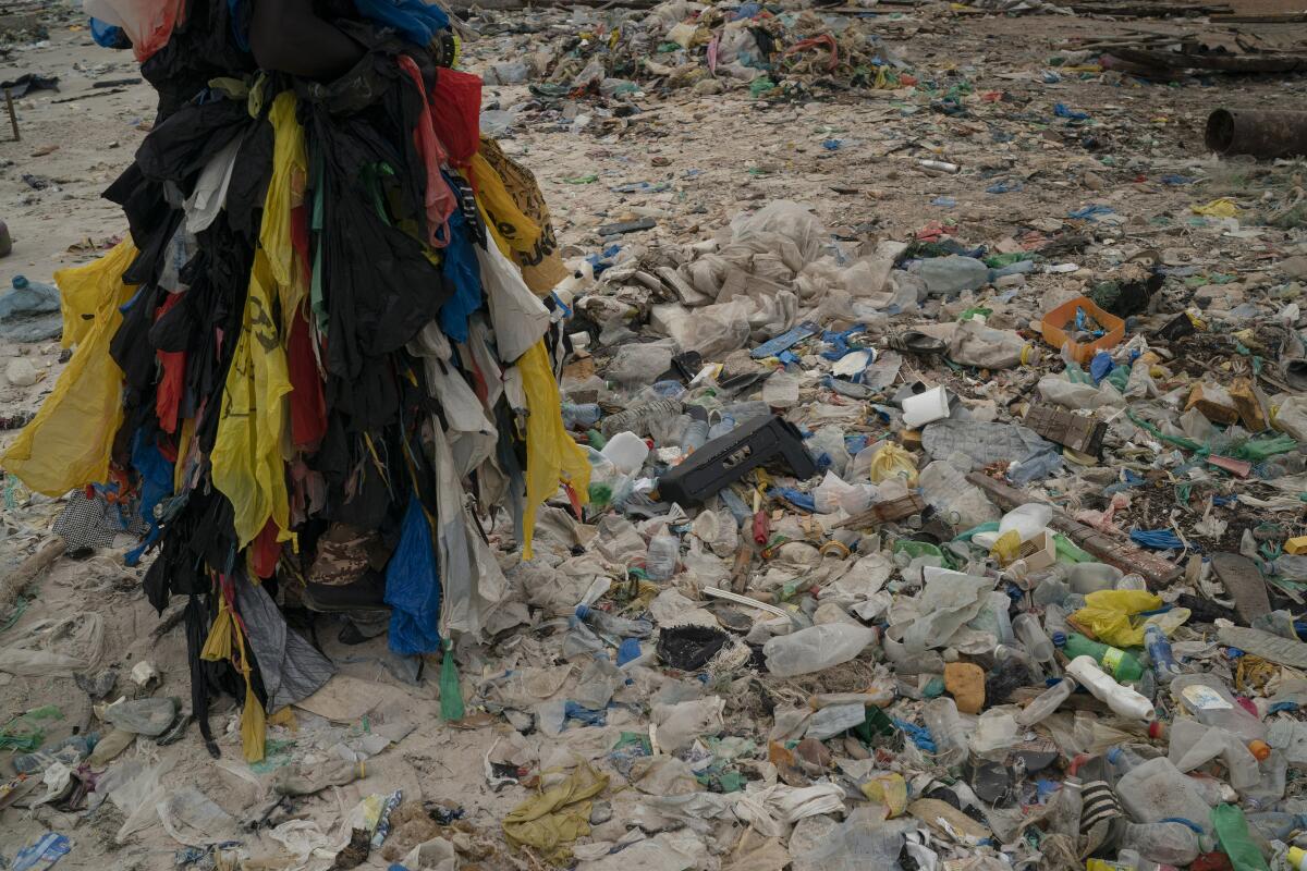 Modou Fall walks on the Yarakh Beach littered by trash and plastics.