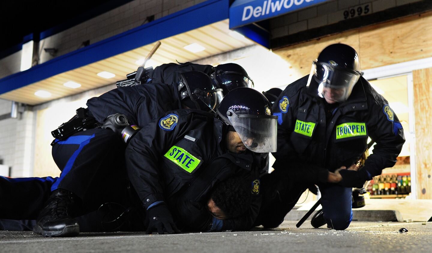 Police officers wrestle a looting suspect to the ground at a Mobil gas station along West Florissant Avenue after a grand jury decision in Ferguson, Mo.