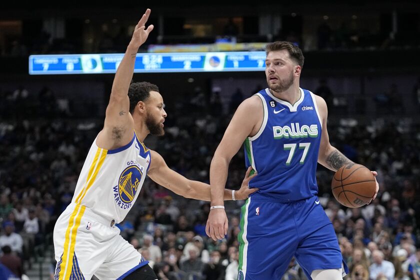 Golden State Warriors' Stephen Curry guards as Dallas Mavericks guard Luka Doncic (77) looks to the basket in the first half of an NBA basketball game, Tuesday, Nov. 29, 2022, in Dallas. (AP Photo/Tony Gutierrez)