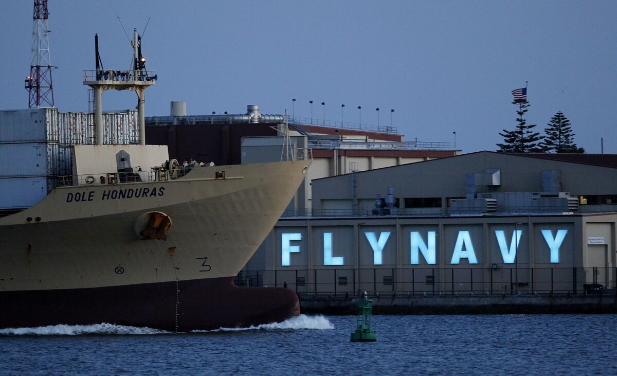 A Dole ship moves by the "Fly Navy" sign that is illuminated at North Island Naval Air Station.