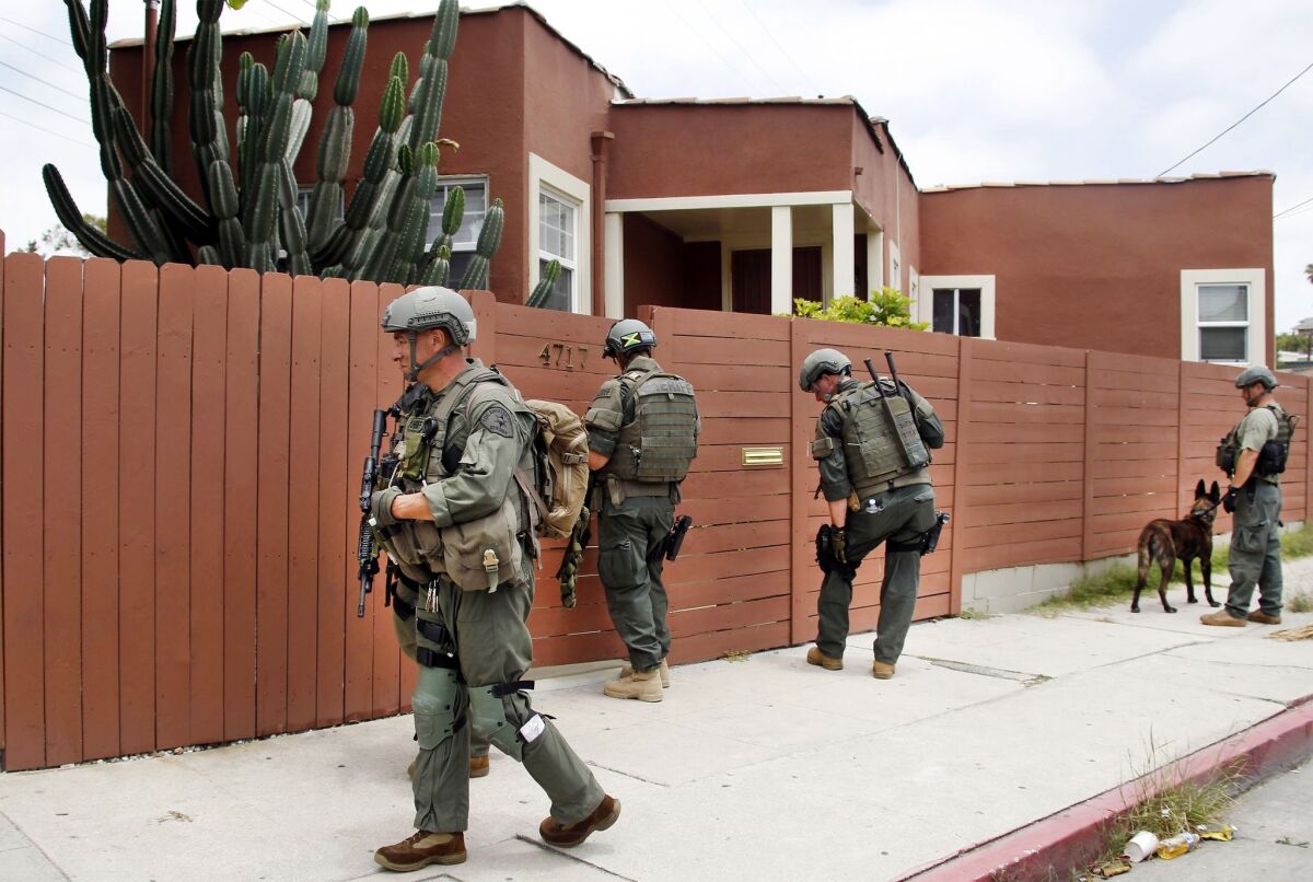 Los Angeles sheriff's deputies search a city street for a gunman Tuesday after two police officers were shot and wounded in an attack outside a police station in the Mid-City area.