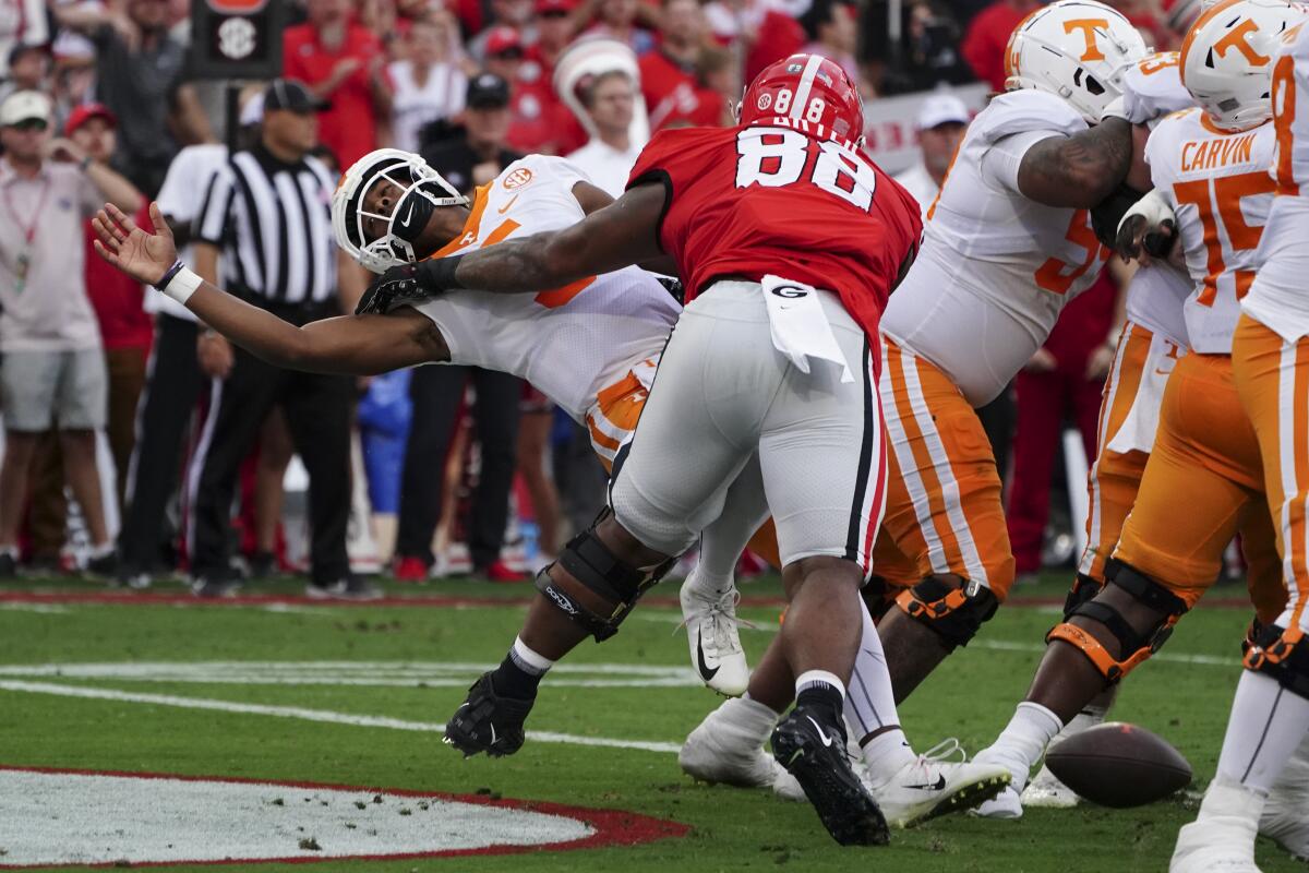 Tennessee quarterback Hendon Hooker, left, fumbles as he is hit by Georgia defensive lineman Jalen Carter (88) in the end zone during the first half of an NCAA college football game Saturday, Nov. 5, 2022, in Athens, Ga. Tennessee recovered the ball and avoided a safety. (AP Photo/John Bazemore)
