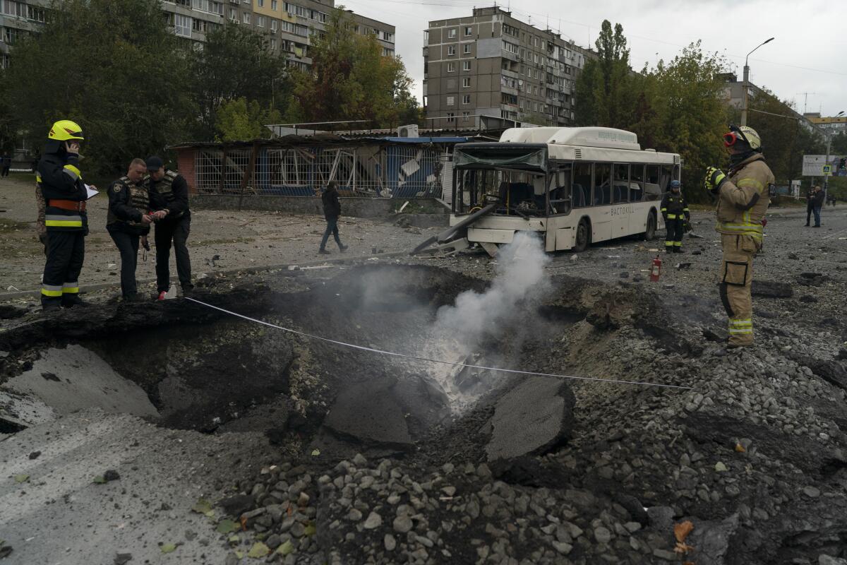 Bomberos y agentes de la policía trabajan en el sitio donde una explosión creó un cráter en una calle tras un ataque ruso