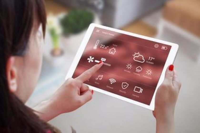 Woman use application for smart home control on tablet. Interior of living room in the background.