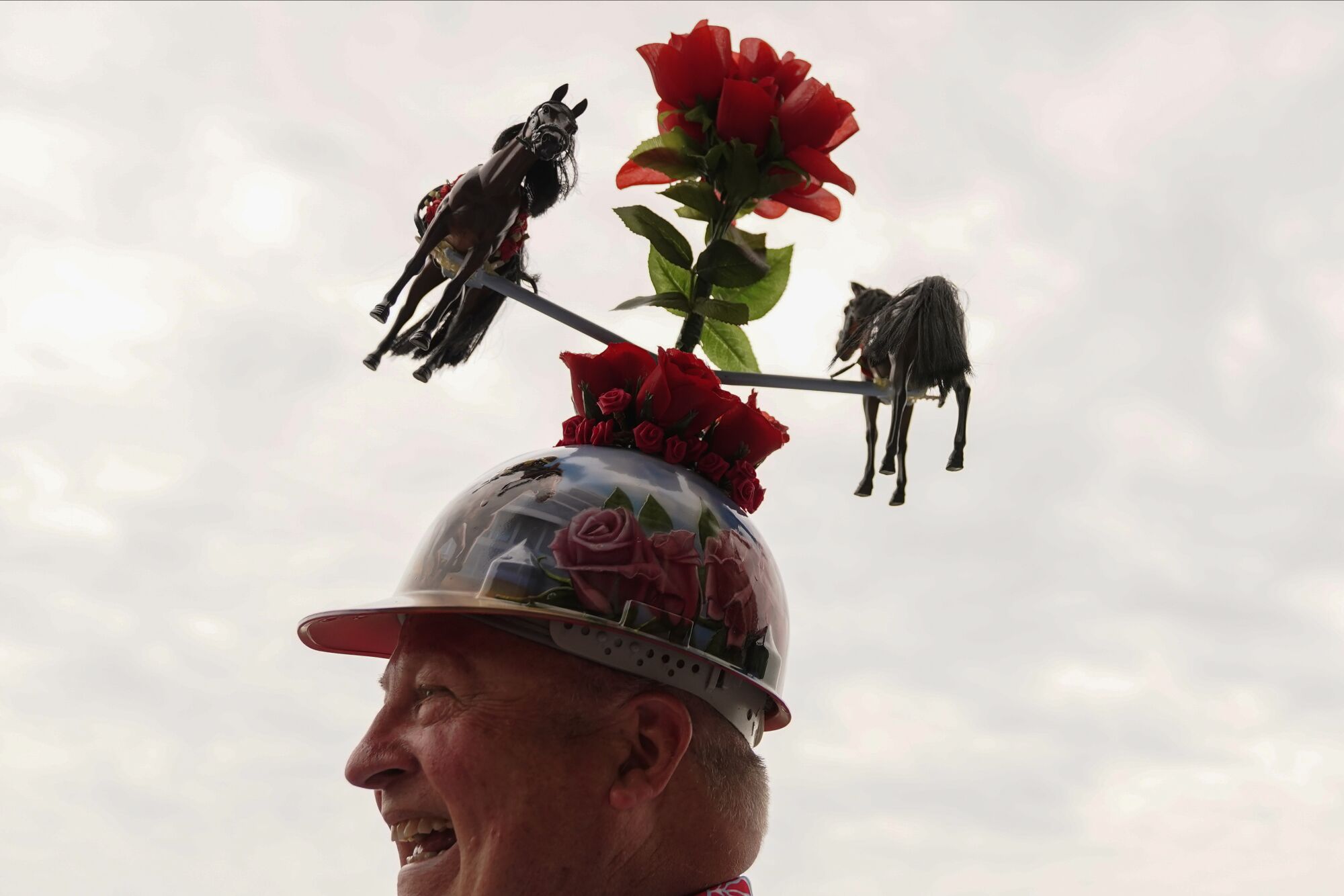 Skip Koepnick from Wyoming wears a jockey hat decorated with horses while walking on the grounds of Churchill Downs.