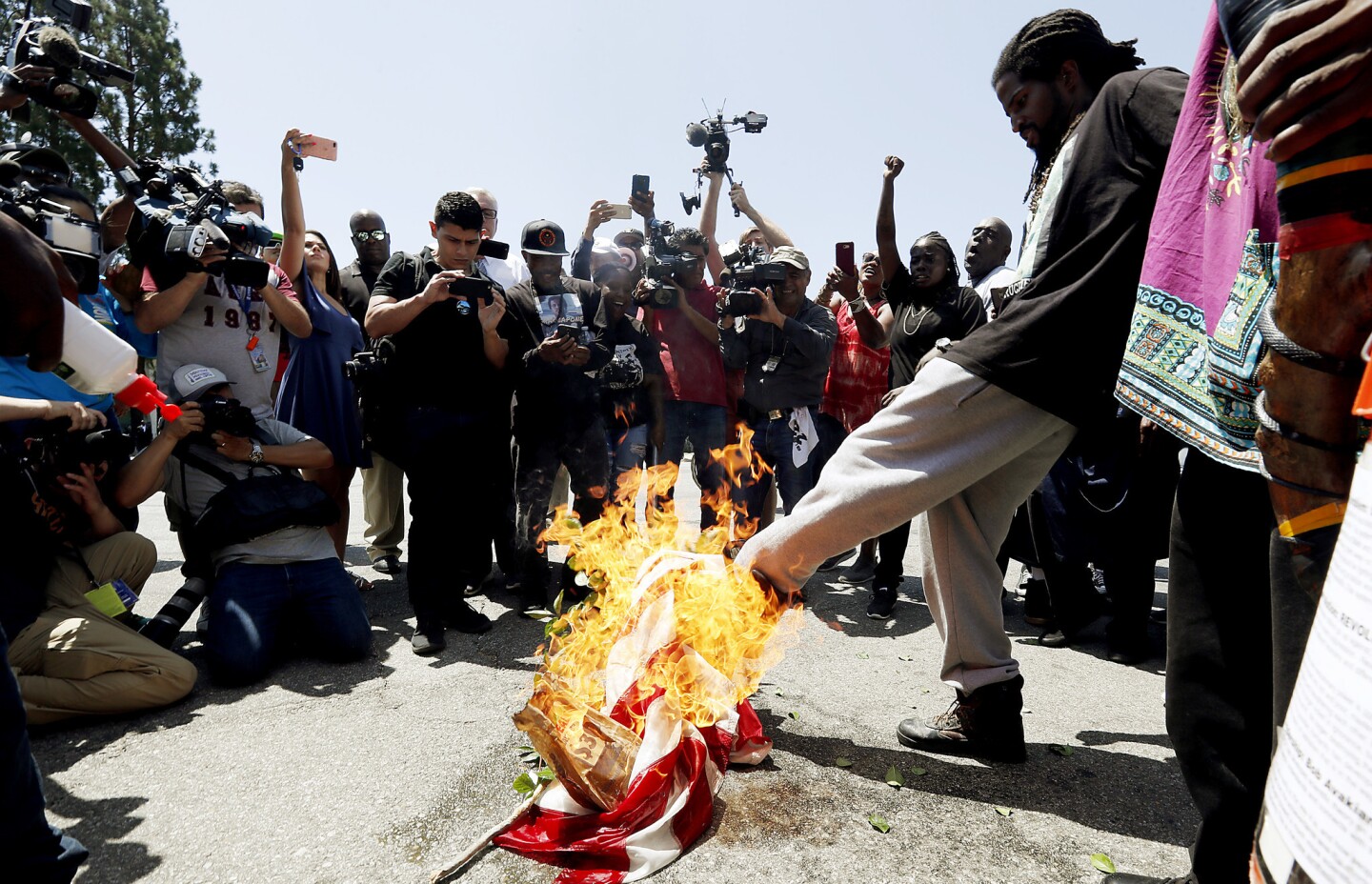 Counterprotesters burn an American flag outside the South L.A. office of Rep. Maxine Waters on Thursday. They gathered after hearing that the Oath Keepers were planning to demonstrate at the site, but the far-right anti-government group was a no-show.