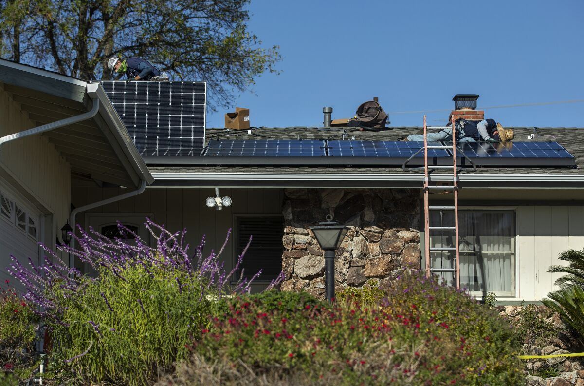 Workers install rooftop solar panels 