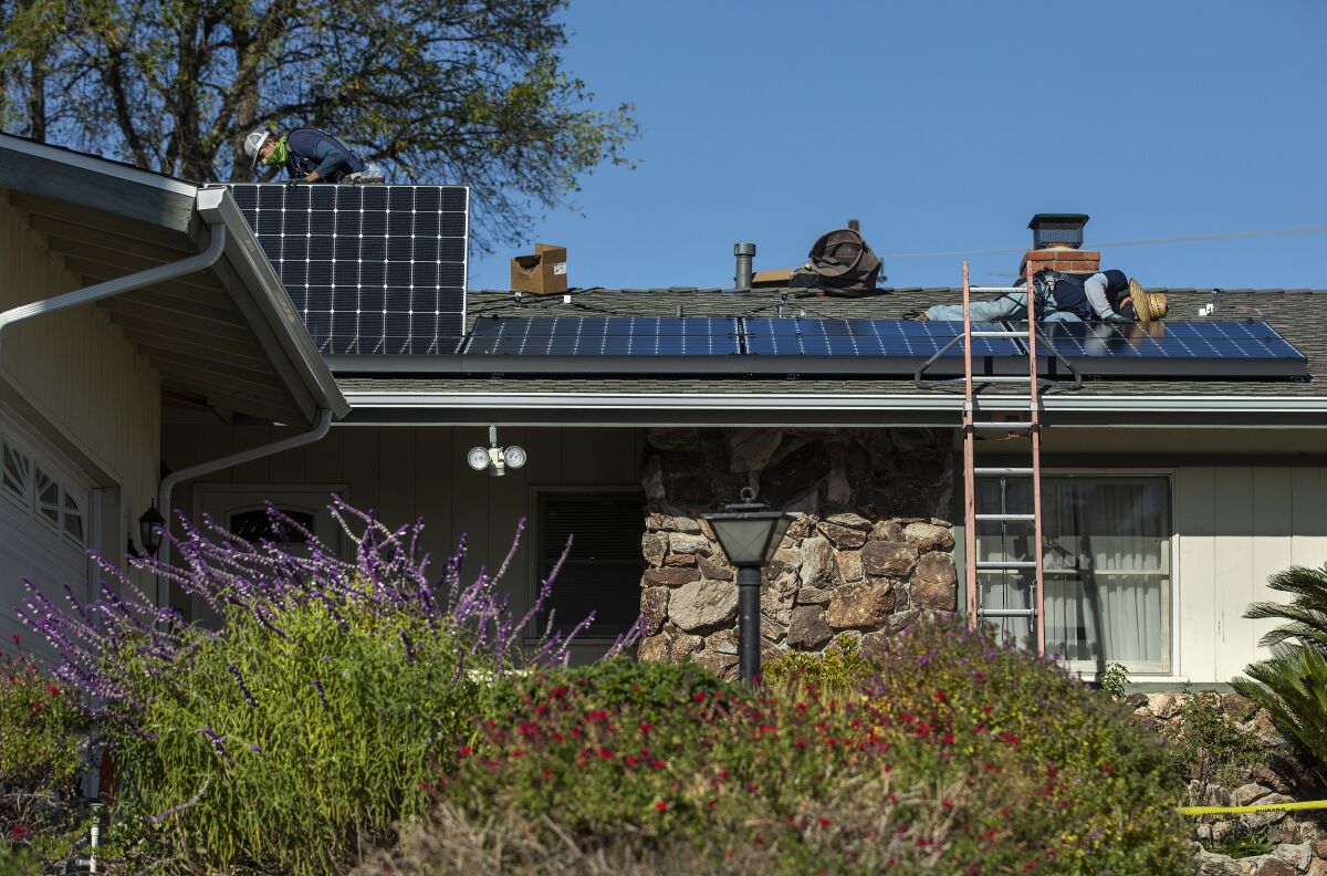 Workers install rooftop solar panels