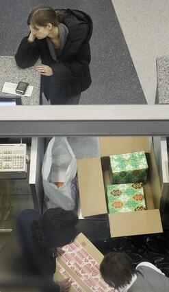 A passenger at an American Airlines ticket counter waits as her wrapped Christmas presents are boxed up to be checked as baggage at Chicago's O'Hare International Airport Wednesday, Dec. 24, 2008