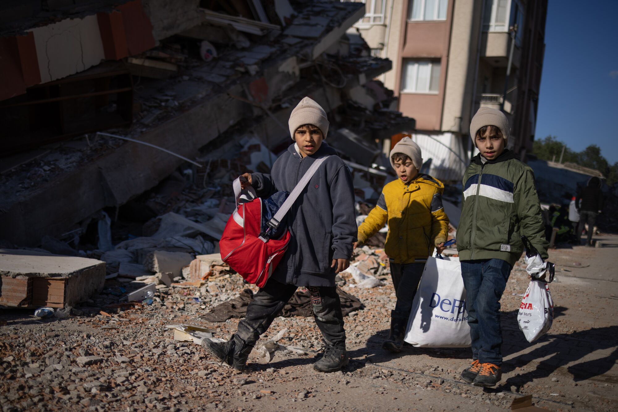 Children walk past destroyed buildings in Antakya, Turkey.
