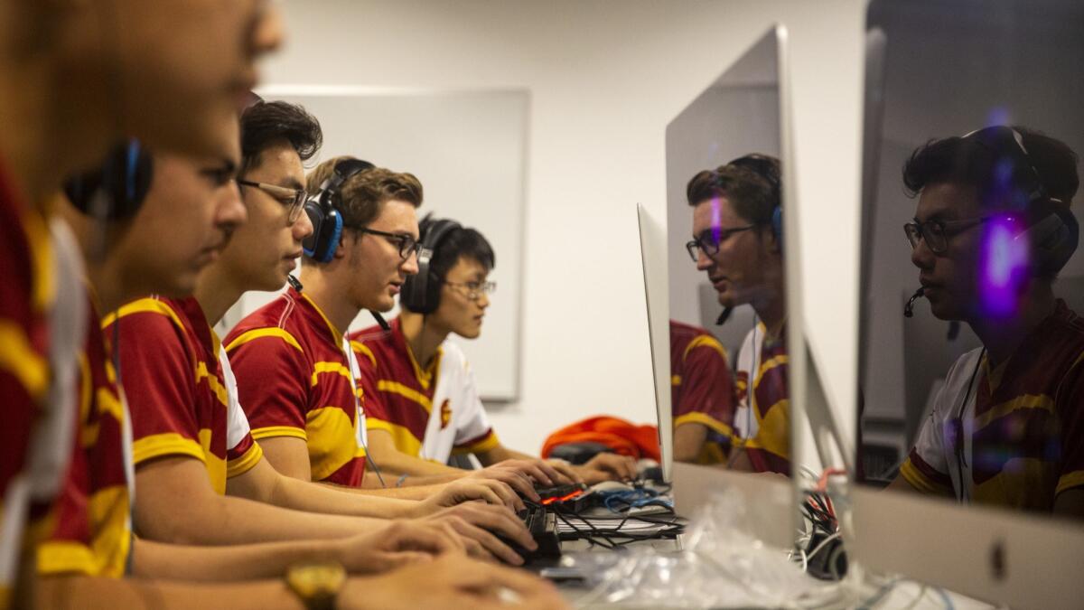 Members of the USC varsity esports team are reflected in the screens of their monitors during practice in a basement lab.