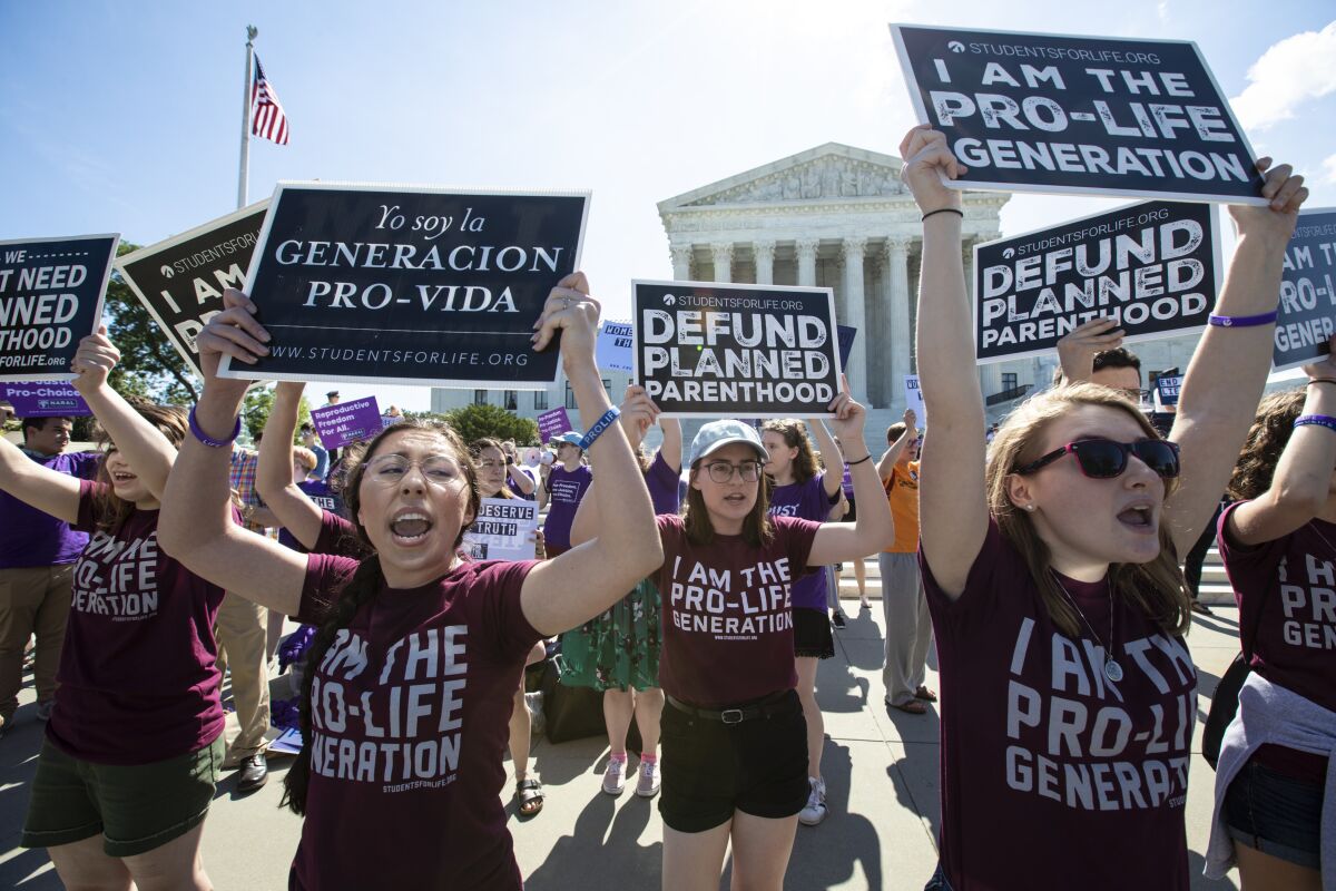 FILE - In this June 25, 2018 file photo, pro-life and anti-abortion advocates demonstrate in front of the Supreme Court in Washington. Republican lawmakers in at least a half dozen GOP-controlled states already are talking about copying a Texas law that bans abortions after a fetal heartbeat is detected. The law was written in a way that was intended to avoid running afoul of federal law by allowing enforcement by private citizens, not government officials. (AP Photo/J. Scott Applewhite, File)