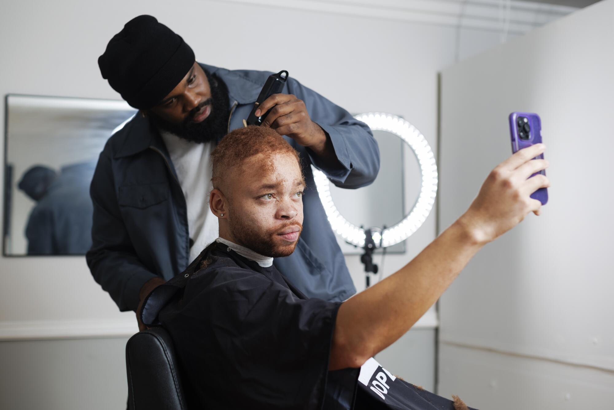 Jamal Rhodes applies a hair kit to John-Jonne Smith's scalp.