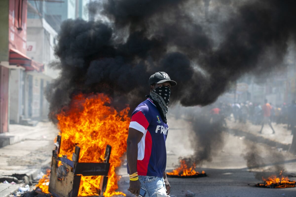 A protester walks past burning barricades during a protest demanding the resignation of President Jovenel Moise in Port-au-Prince, Haiti, Saturday, Oct. 17, 2020. The country is currently experiencing a political impasse without a parliament and is now run entirely by decree under Moise. ( AP Photo/Dieu Nalio Chery)