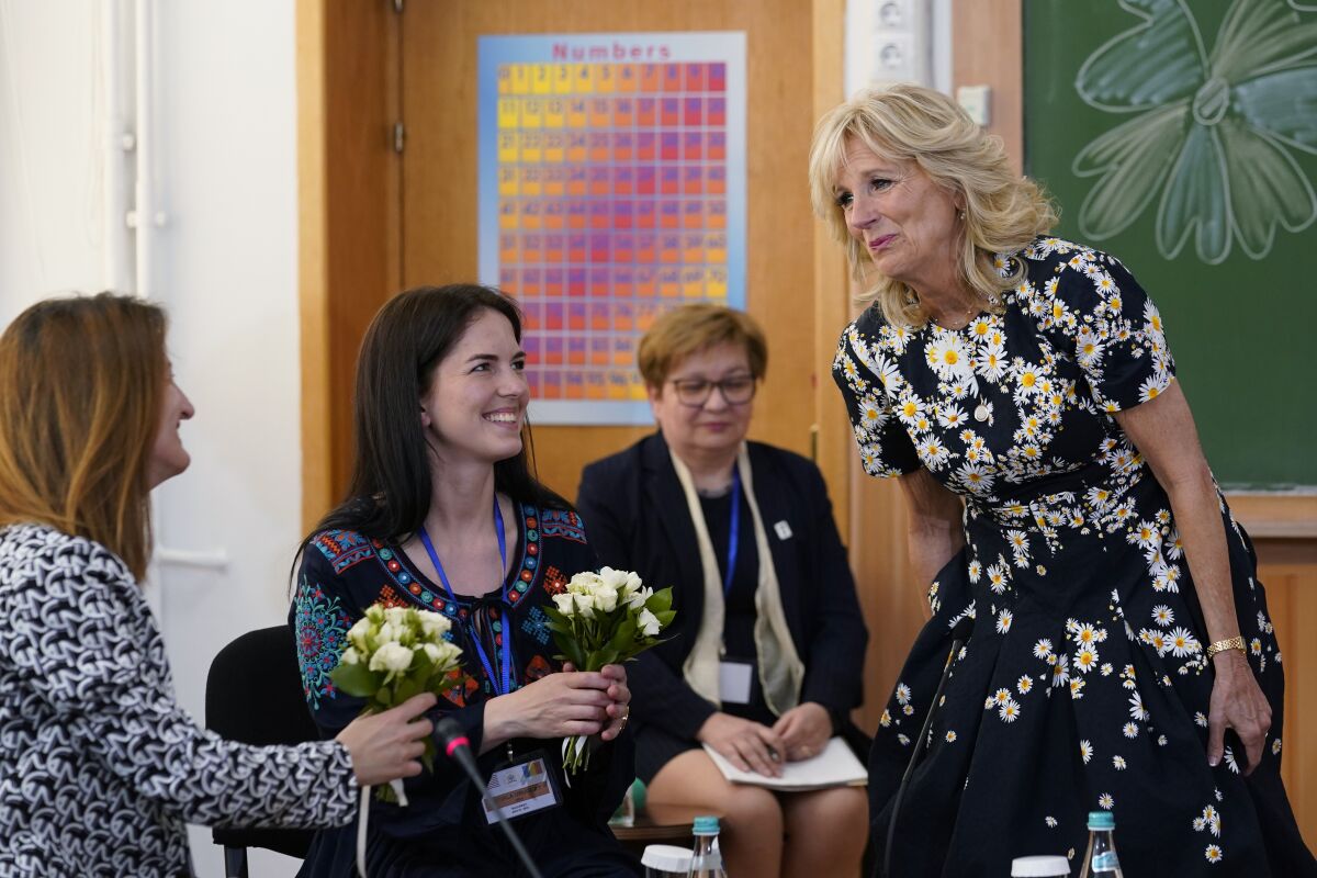 First lady Jill Biden, right, gives flowers to teacher Anastasia Konolovalova, left, and Svitlana Gollyak, a mother who had to leave her home in Ukraine, during a visit to the Școala Gimnaziala Uruguay, or Uruguay School, in Bucharest Romania, Saturday, May 7, 2022. Biden visited several classrooms to visit with children and the educators who are helping teach displaced Ukrainian children. (AP Photo/Susan Walsh, Pool)
