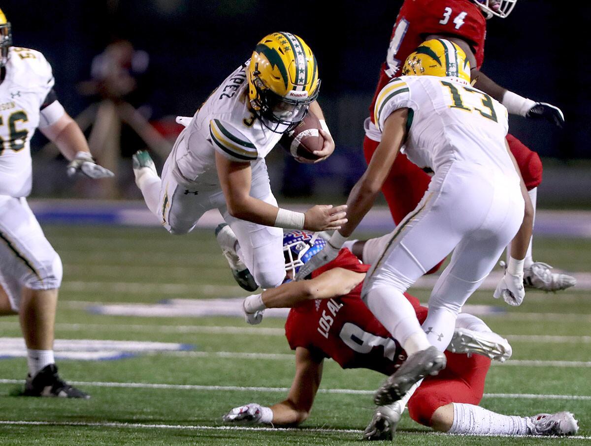 Edison High running back Kobe Lopez (3) gets tripped up by Los Alamitos' Bobby Blandino (9) in a Sunset League game at Cerritos College in Norwalk on Friday.