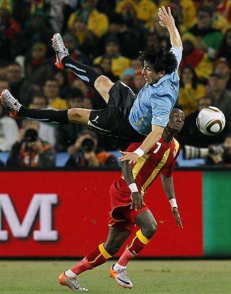 Uruguay's Jorge Fucile, front, takes a fall as he competes for the ball with Ghana's Samuel Inkoom during the World Cup quarterfinal soccer match between Uruguay and Ghana at Soccer City in Johannesburg, South Africa, Friday, July 2, 2010.