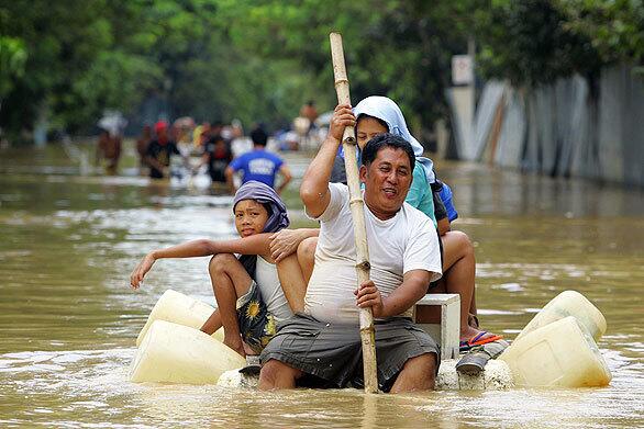 A man paddles his family on a makeshift raft as floodwaters remain high in suburban Pasig, east of Manila. Rescuers pulled more bodies from swollen rivers and debris-strewn streets Tuesday from massive flooding from Tropical Storm Ketsana in the northern Philippines, while two new storms brewing in the Pacific threatened to complicate relief efforts.