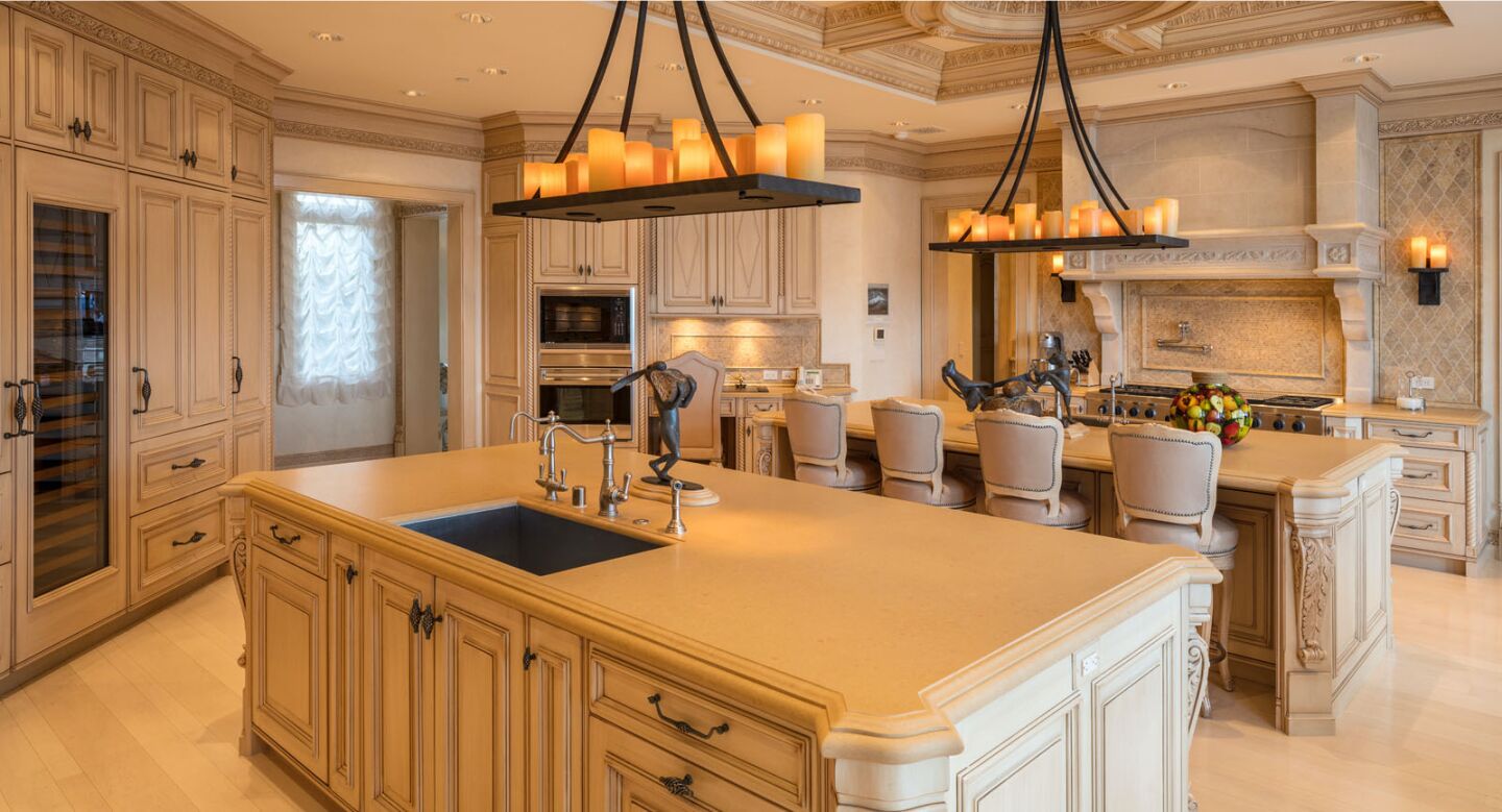 Glowing-candle chandeliers hang above two kitchen islands, one with seating for four.