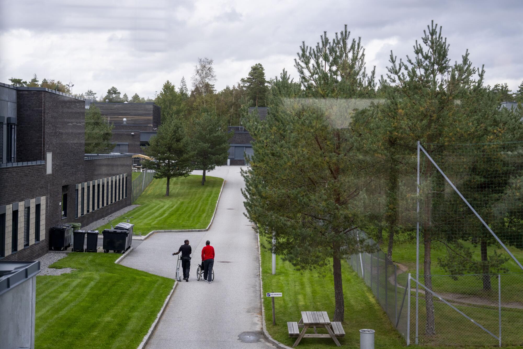 Two people walk down a path at Halden prison