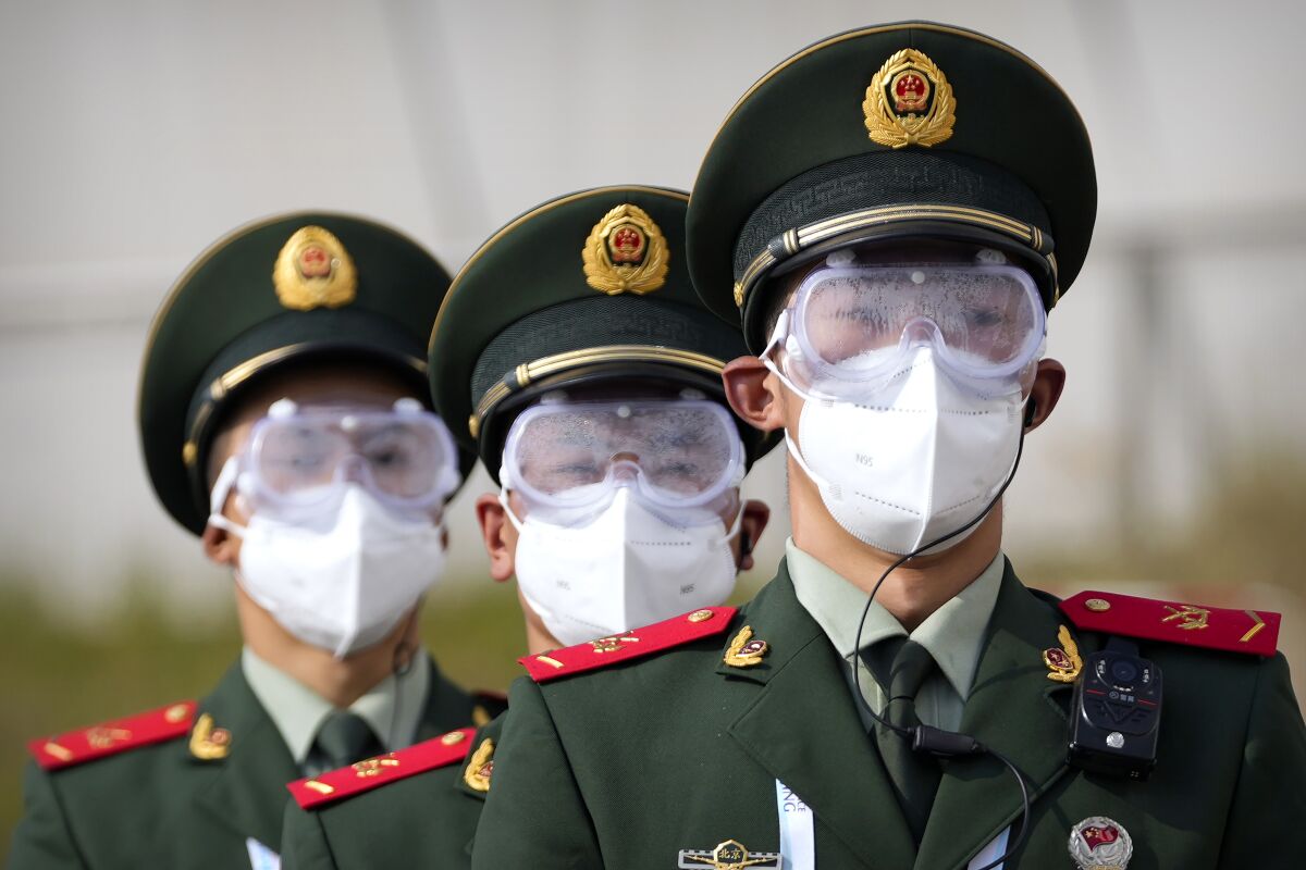 Chinese paramilitary police wearing goggles and face masks march in formation at the Yanqing National Sliding Center during an IBSF sanctioned race, a test event for the 2022 Winter Olympics, in Beijing, Monday, Oct. 25, 2021. A northwestern Chinese province heavily dependent on tourism closed all tourist sites Monday after finding new COVID-19 cases. The spread of the delta variant by travellers and tour groups is of particular concern ahead of the Winter Olympics in Beijing in February. Overseas spectators already are banned, and participants will have to stay in a bubble separating them from people outside. (AP Photo/Mark Schiefelbein)