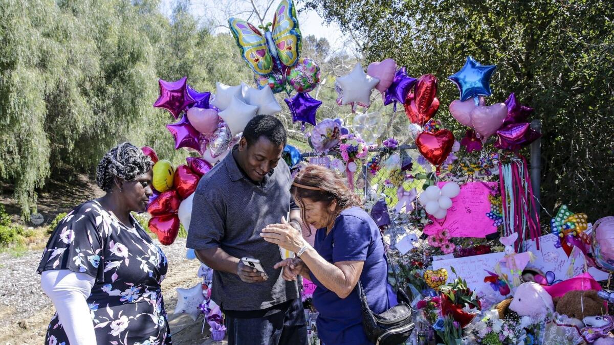 Anthony Jones shares some memories of daughter Trinity Jones on his phone with Mary Montes at a makeshift memorial in Hacienda Heights where the girl's body was discovered. Barbara Jones, the girl's grandmother, is at left.