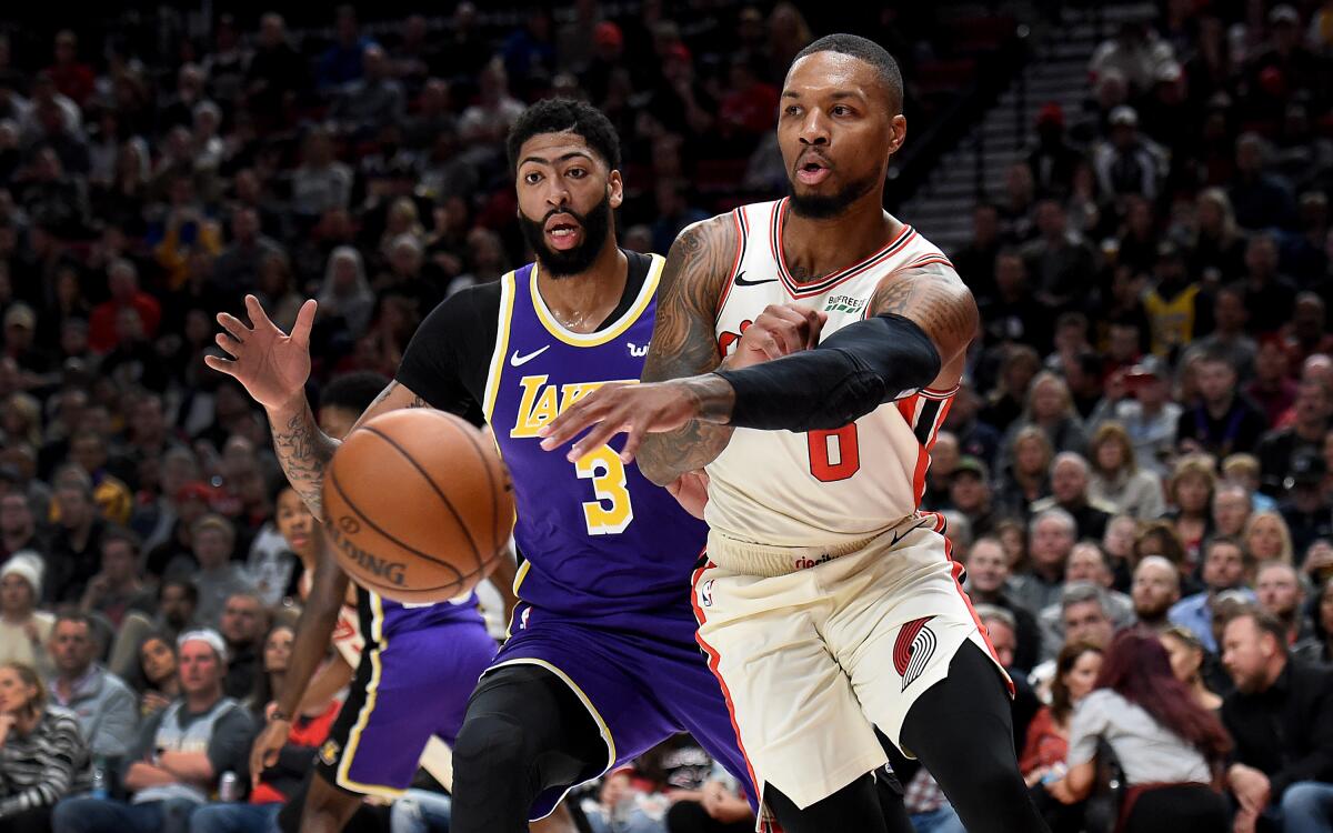 Damian Lillard of the Trail Blazers passes the ball as Anthony Davis defends.