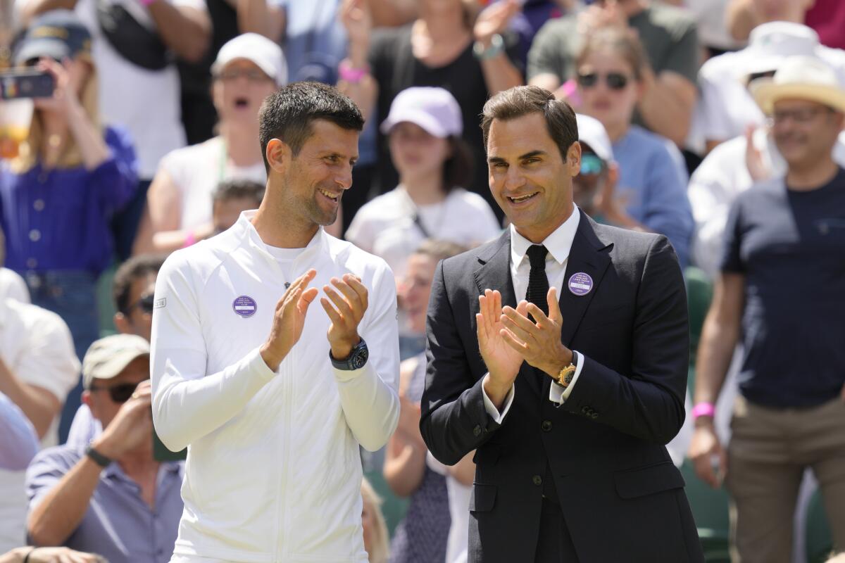 Serbia's Novak Djokovic and Switzerland's Roger Federer applaud during a 100 years of Centre Court celebration on day seven of the Wimbledon tennis championships in London, Sunday, July 3, 2022. (AP Photo/Kirsty Wigglesworth)
