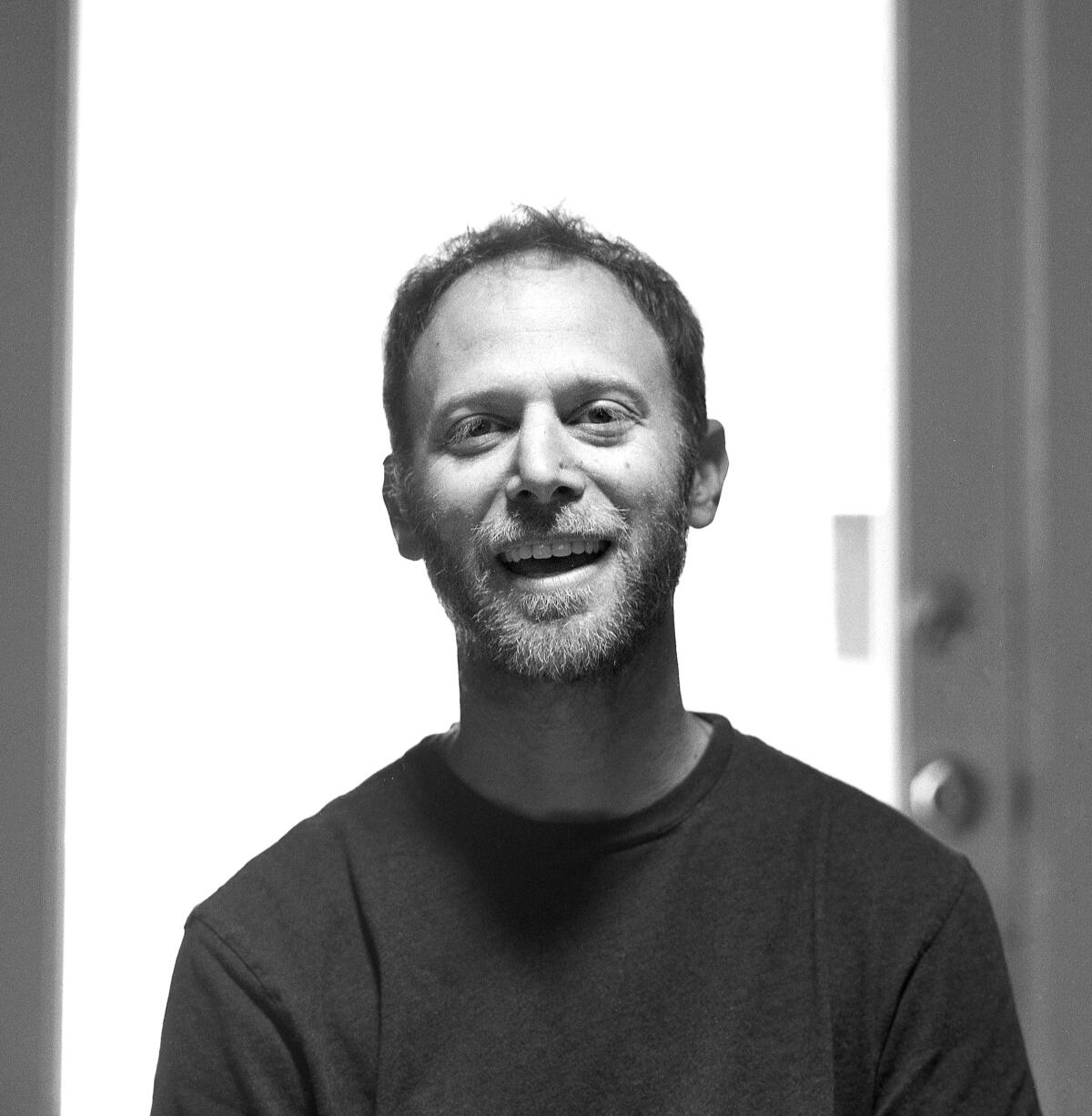 A black and white photo shows a smiling Steve Roden wearing a dark sweatshirt.