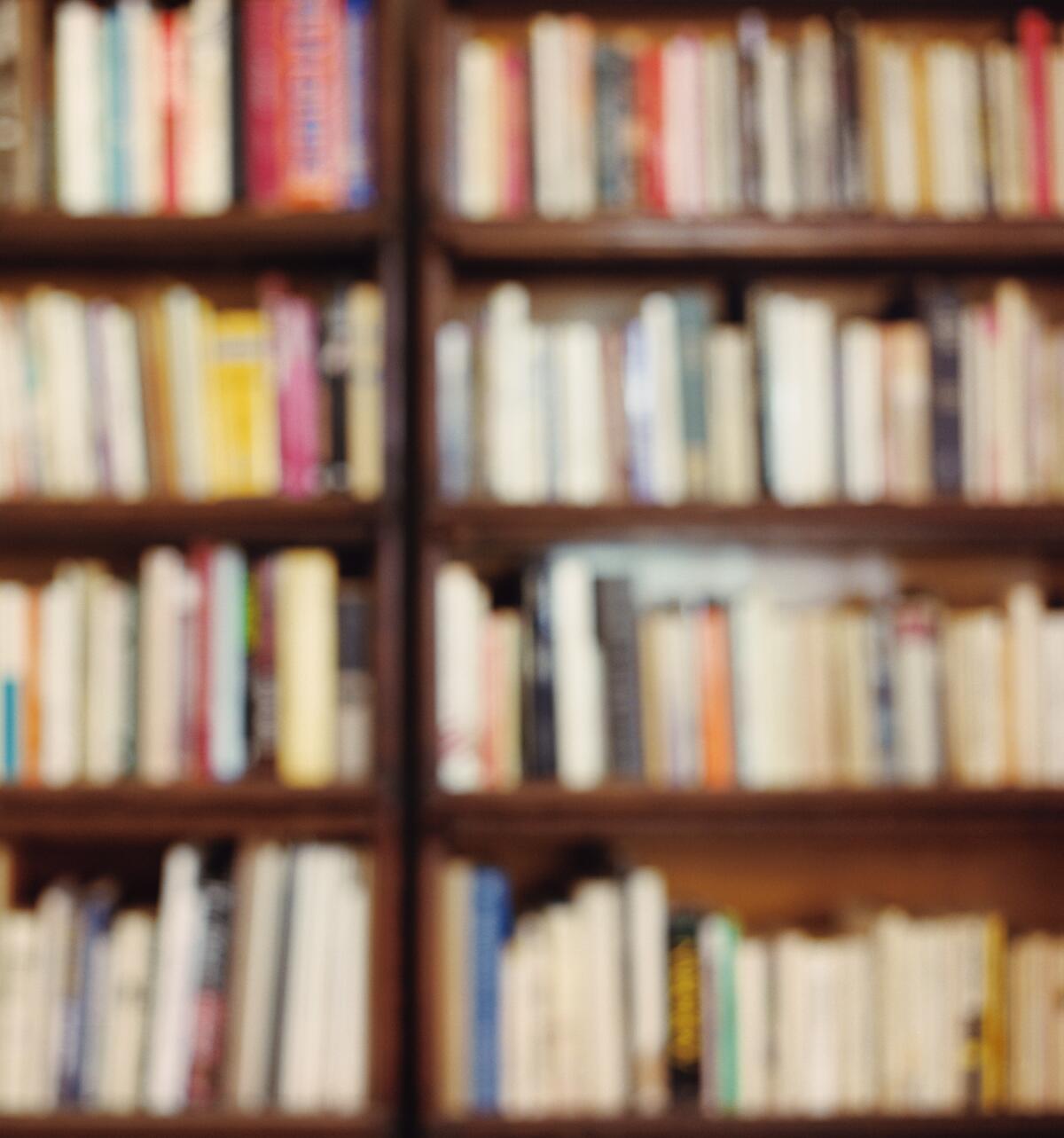 A blurry photograph of rows of books on shelves.